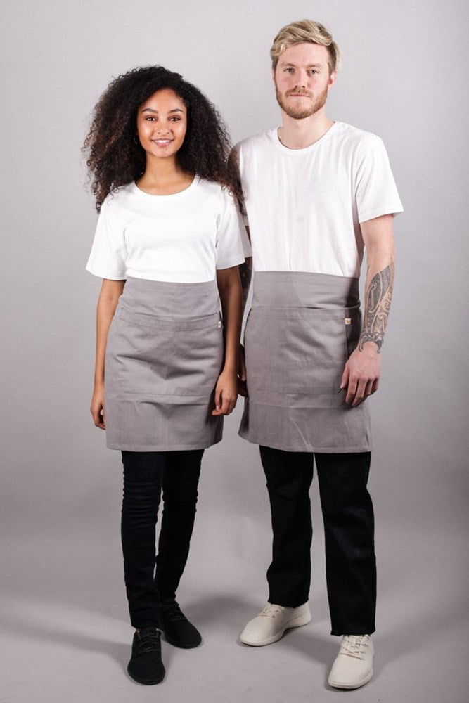 Female and male models in studio wearing Bliss Apron Half Length - Grey against grey background