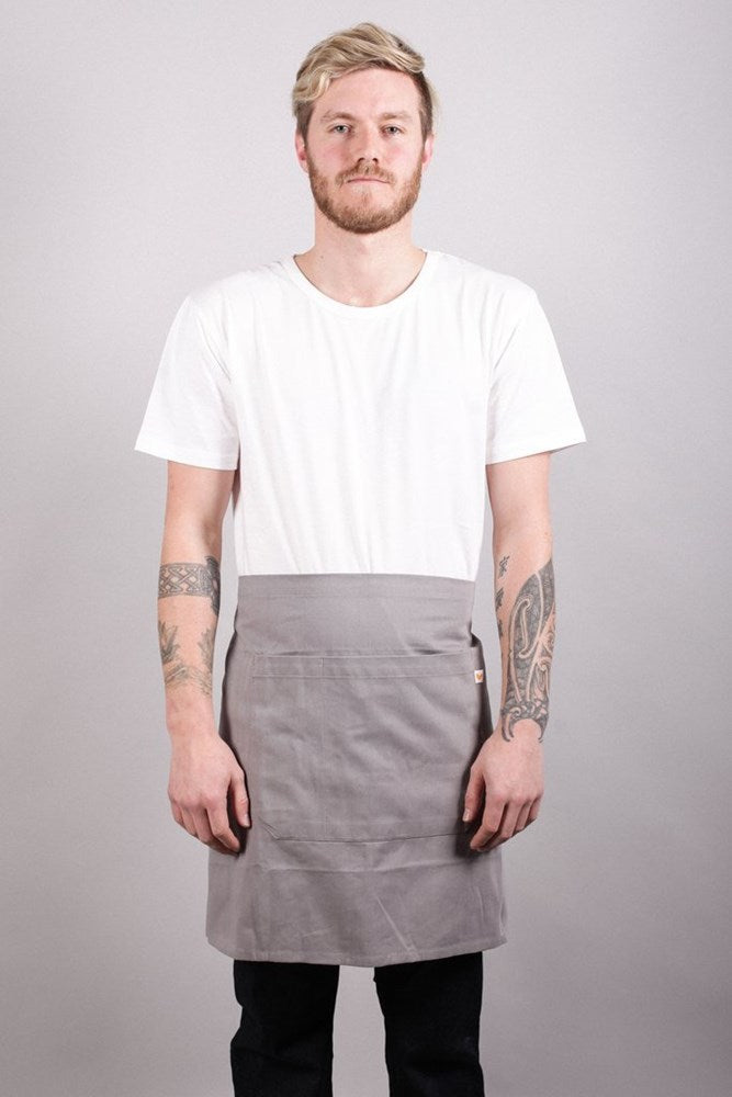 Male model in studio wearing Bliss Apron Half Length - Grey against grey background