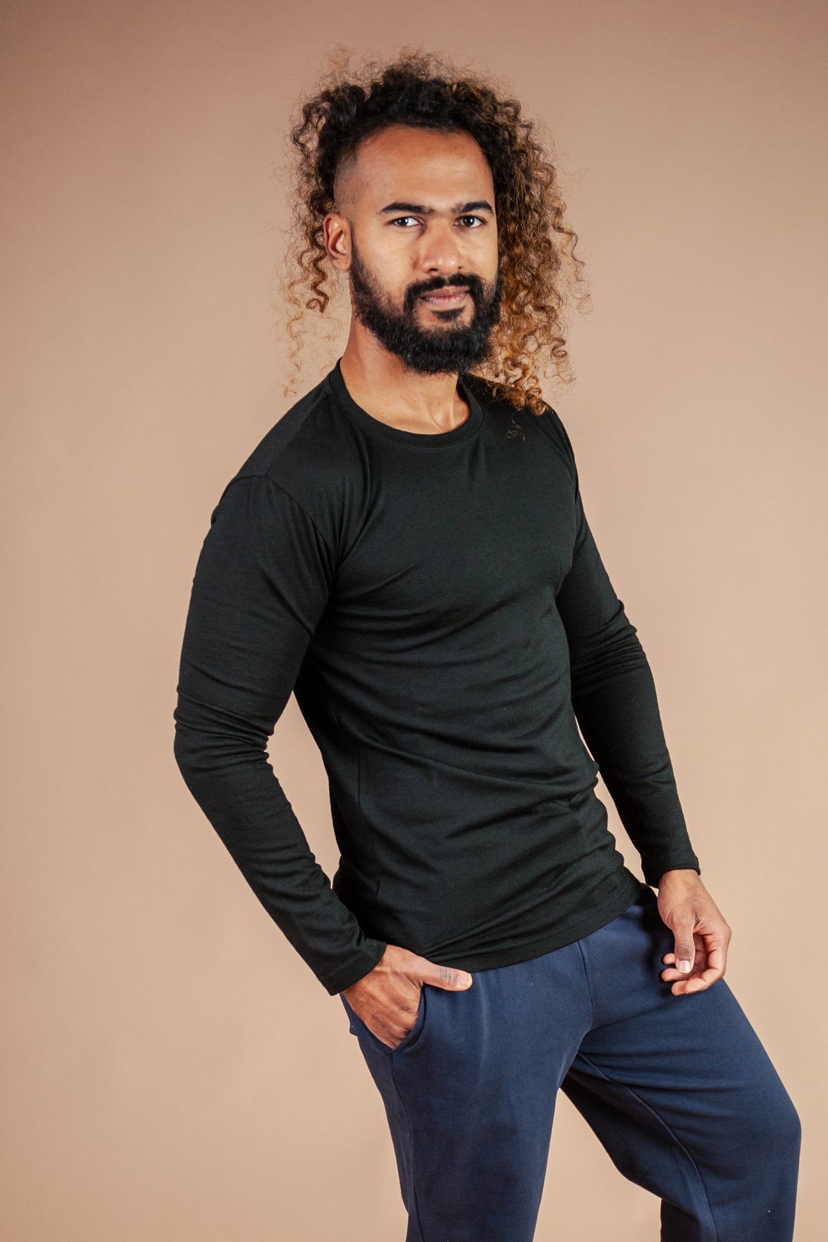 Male model wearing black marvel merino long sleeve tee against brown background