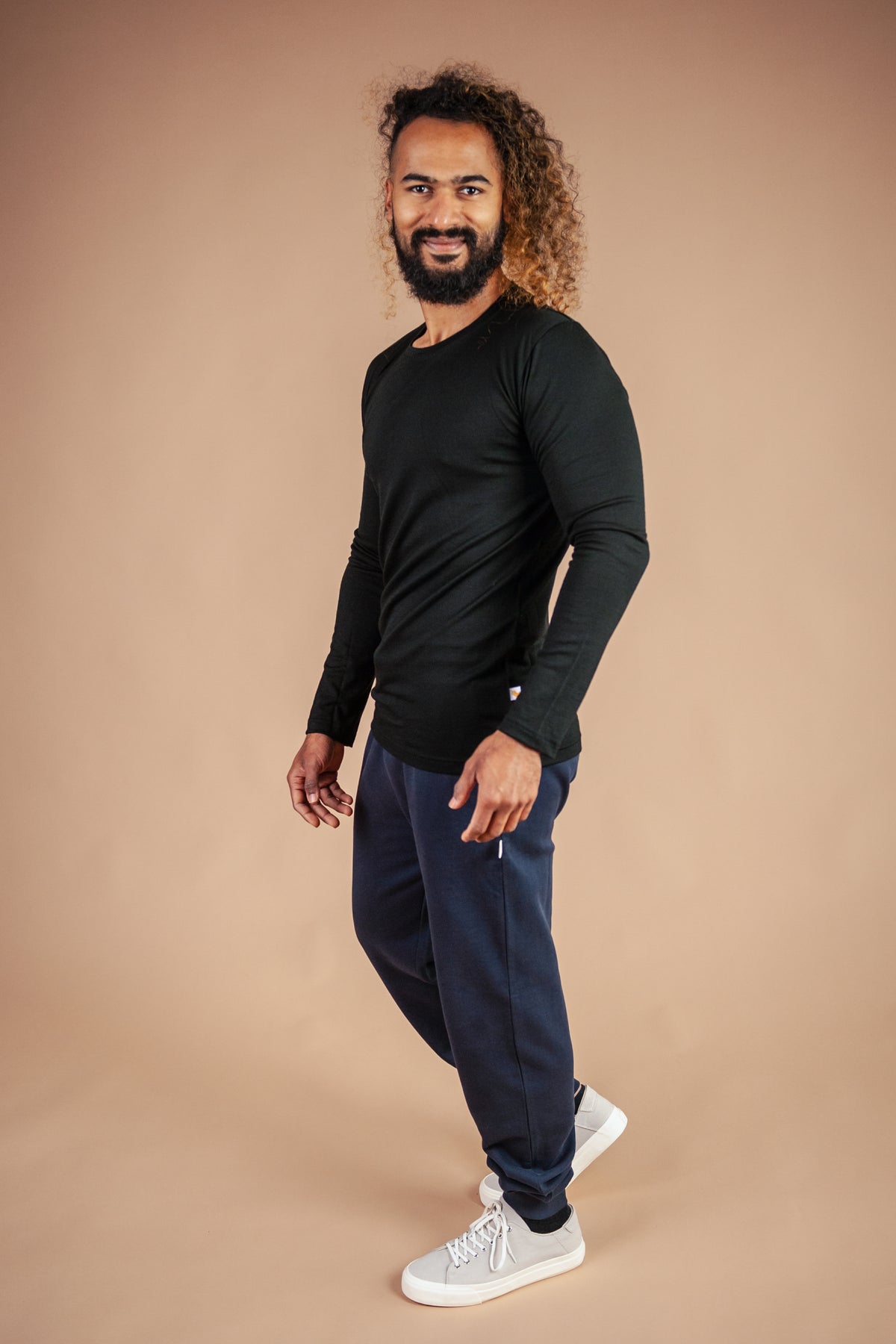 Male model wearing black marvel merino long sleeve tee against brown background