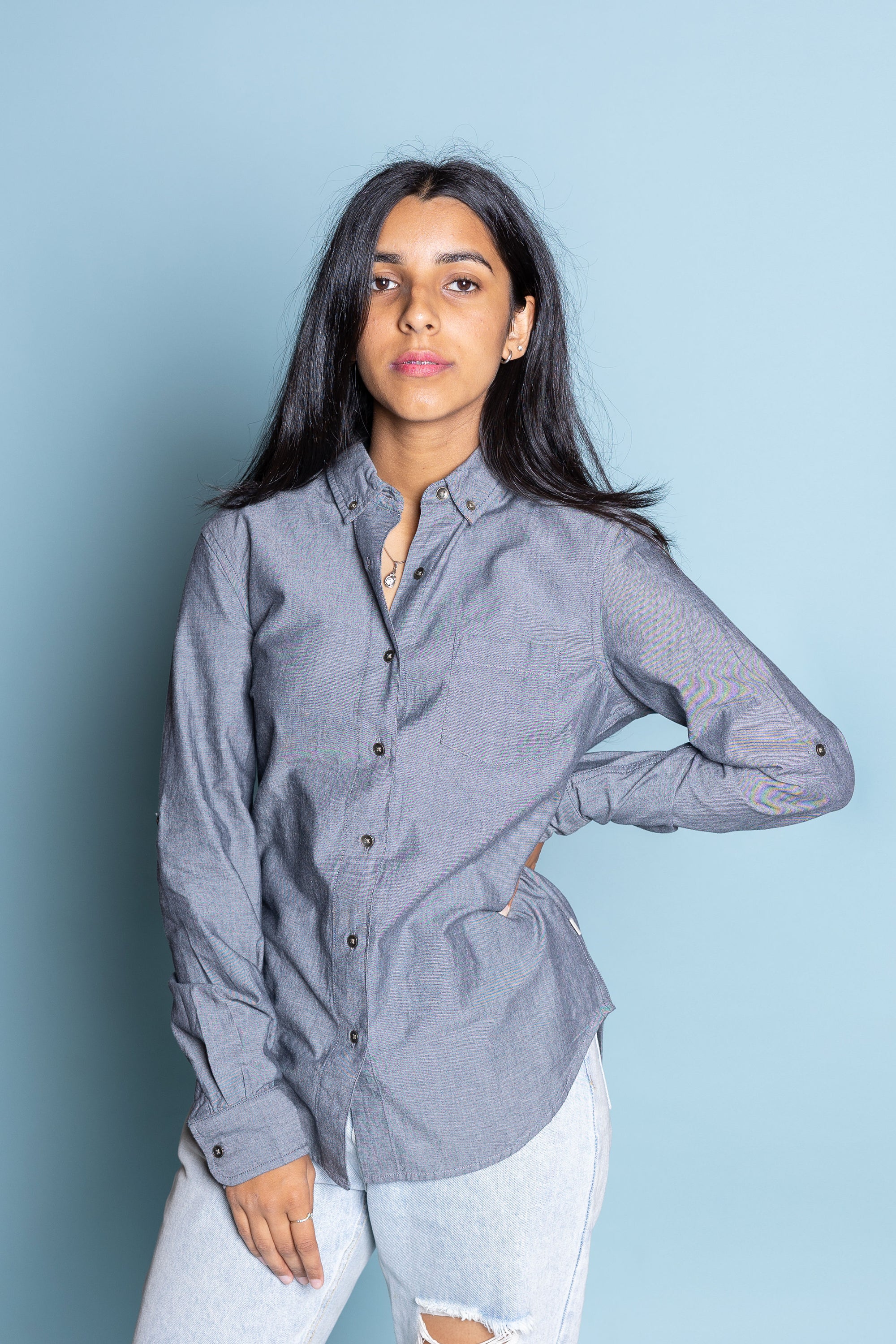 Female model with one hand on hips wearing greywacke Lucy Shirt against blue background